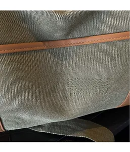 Detail of olive green canvas travel bag with premium brown leather trim and neat stitching