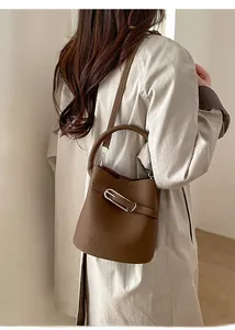 Détail du sac seau en cuir marron foncé avec boucle métallique et bandoulière réglable