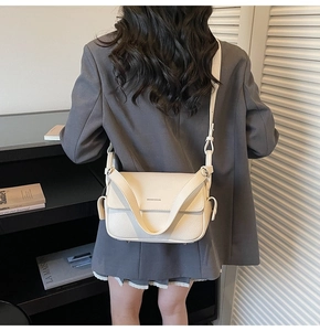 Detail showing beige litchi grain leather texture and brand lettering on crossbody bag