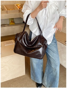 Dettaglio della borsa tote vintage in pelle marrone scuro portata a tracolla