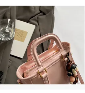 Détail du sac seau rose clair avec ferrures dorées et breloque poupée tendance