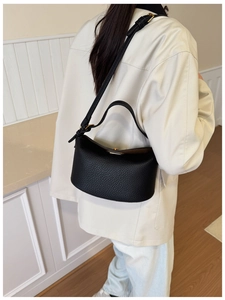 Rear view of a model wearing a black lychee texture crescent bag with an adjustable strap