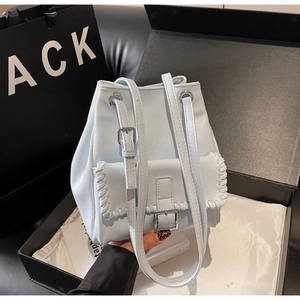Détail d'un sac seau bleu clair avec bords tressés et boucle métallique en boîte cadeau
