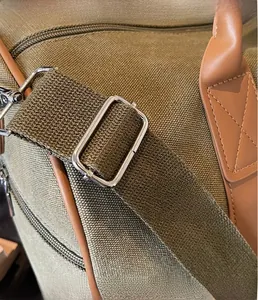 Close-up of silver metal buckle and stitching on olive canvas travel duffel bag
