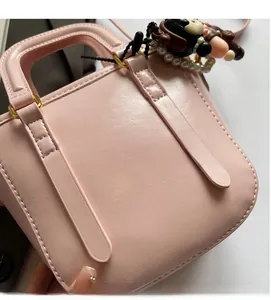 Détail d'un sac seau en cuir PU rose avec breloque de dessin animé et chaîne en perles