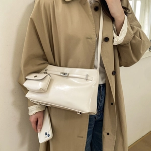 Dettaglio della borsa a tracolla in vernice bianca con chiusura rotante e mini pochette
