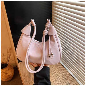 Detailed view of half-moon bag featuring knot strap and silver metallic ball charms