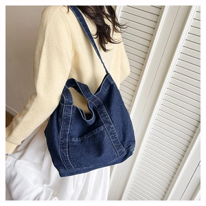 Detail of blue denim tote bag showing white contrast stitching and soft fabric texture
