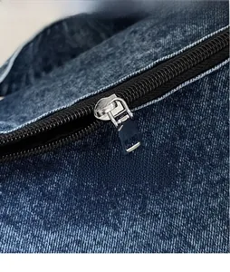 Close-up of polished silver metal zipper head on dark blue denim tote bag detail