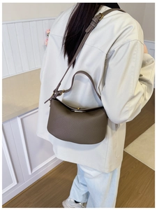 Detailed view of coffee brown lychee pattern leather crescent bag with adjustable strap