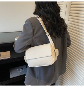 Detailed view of cream-colored litchi grain leather shoulder bag with flap and logo