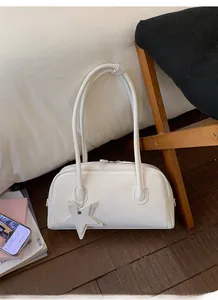Detail of a white minimalist shoulder bag featuring double straps and a star pendant accessory