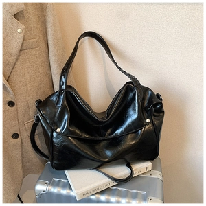 Dettaglio borsa tote in pelle cerata nera con borchie d'argento in scena di viaggio
