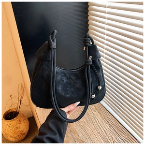 Detail of black suede dumpling bag featuring woven rope handle and silver metal beads
