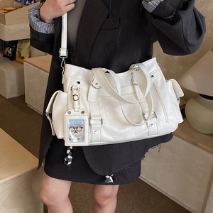 Dettaglio della borsa tote bianco sporco con tasche multiple e ciondolo a forma di orso