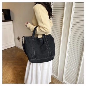 Detail of black canvas tote bag with white contrast stitching and long shoulder straps