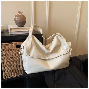 Dettaglio di una grande borsa tote bianco sporco con texture lucida a pieghe e borchie