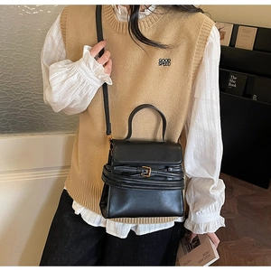 Vue détaillée du sac à bandoulière en cuir noir mat avec boucle sur la tenue