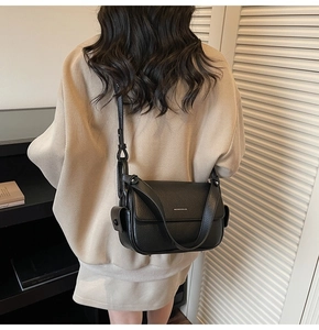 Detail of black litchi texture leather crossbody bag with white logo and adjustable strap