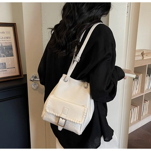 Détail du sac seau crème montrant les bords surpiqués tissés et la boucle carrée en métal