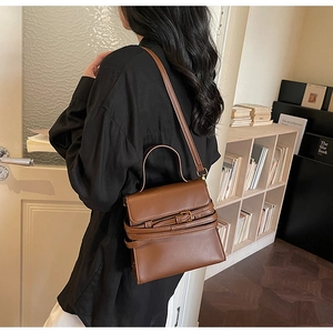 Détail du sac à main en cuir marron foncé avec sangles parallèles et boucles métalliques vintage