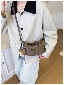 Detail of elephant grey leather Lindy bag with vintage gold clasp and plush bear charm