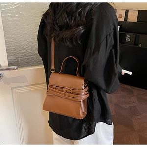 Détail du sac vintage en cuir marron avec boucle de ceinture et finitions dorées chic