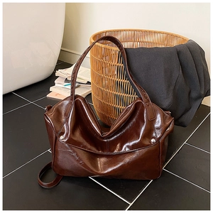 Dettaglio borsa tote in pelle marrone scuro lucida con rivetti e ampia tracolla laterale
