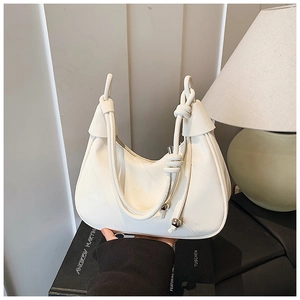 Detail of cream hobo bag with unique knot handle design and silver metal ball charm