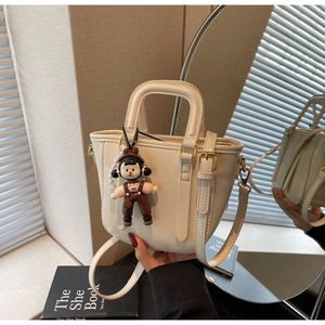 Détail du sac seau blanc cassé avec breloque poupée perle et bandoulière réglable