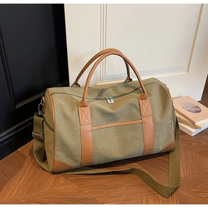 Detail of army green travel bag with brown leather handles and adjustable shoulder strap