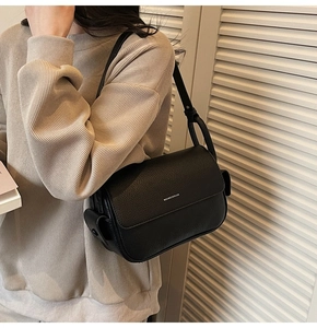 Detail of black lychee grain leather crossbody bag showing the adjustable strap and brand logo