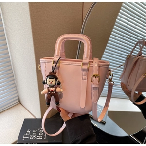 Vue détaillée du sac seau en cuir rose avec breloque mignonne et finitions dorées