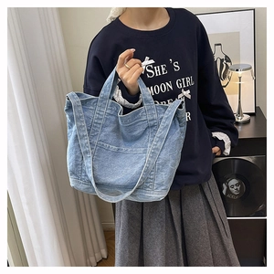 Detail view of light blue washed denim tote bag with external pockets and shoulder straps