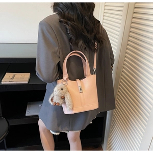 Bolso saco rosa de piel granulada con colgante de conejo y cierre metálico elegante