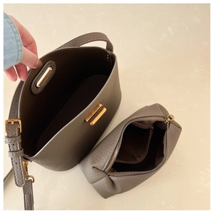 Detailed macro view showing taupe lychee grain leather bucket bag and inner zipper pouch