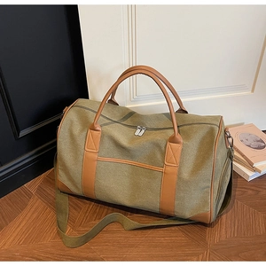 Close-up of olive green canvas travel bag with brown leather handles and side zip pocket