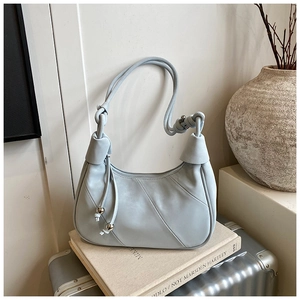 Detail of grey-blue leather crescent bag with knot strap and silver ball charm decoration