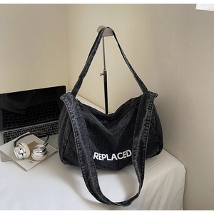 Detailed view of large grey denim tote bag with REPLACED print and office accessories