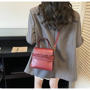 Vue mannequin d'un sac en cuir bordeaux avec boucle et bandoulière réglable