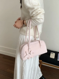 Pink faux leather baguette bag with star charm worn by model in minimalist room