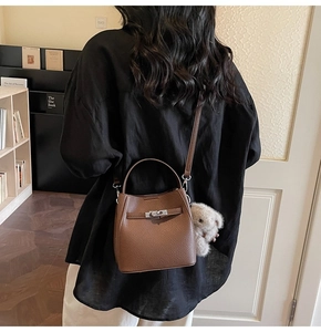 Borsa a secchiello in pelle marrone con chiusura argento e orsetto su una modella