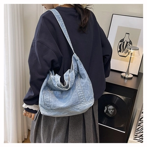 Close-up of light blue denim tote bag with visible stitching in a vintage urban setting