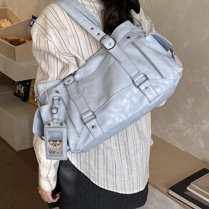 Dettaglio della borsa tote azzurra in finta pelle con fibbie decorative e ciondolo a orsetto