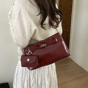 Dettaglio borsa sottobraccio in pelle bordeaux lucida con chiusura e mini pochette