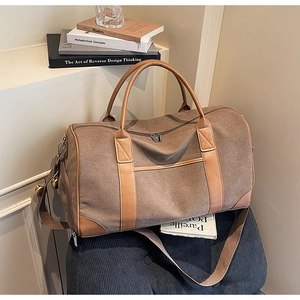 Detail view of large canvas travel duffel bag with leather trim on a blue chair