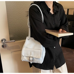 Détail du sac bandoulière en cuir blanc avec rabat tressé et fermoir métallique carré