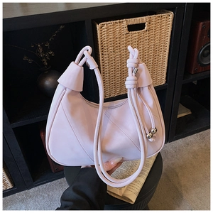 Detail of light pink crescent bag with knotted handle and elegant metal bead charms