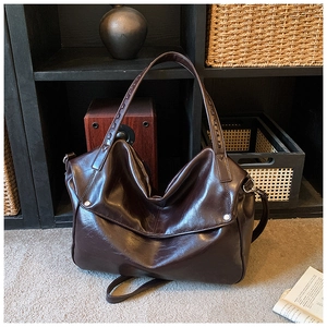 Dettaglio della borsa tote in pelle marrone scuro con rivetti argentati e pieghe