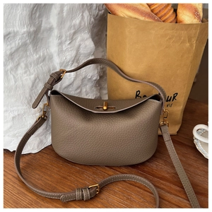 Detail of tan lychee grain leather handbag with gold metal twist lock on wooden desk